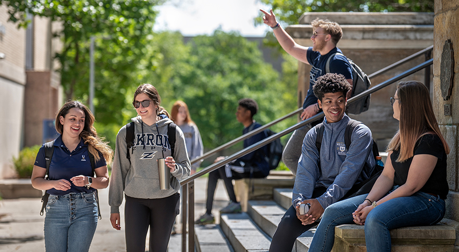 Happy Ͽ¼ students walking out of and in front of Buchtel Hall on The University of Akron campus.
